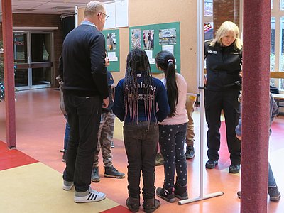 a man and school children standing in front of a presentation wall with photos