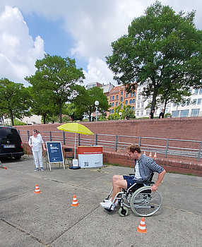 Ein Mann im Rollstuhl fährt Slalom um kleine Verkehrshütchen